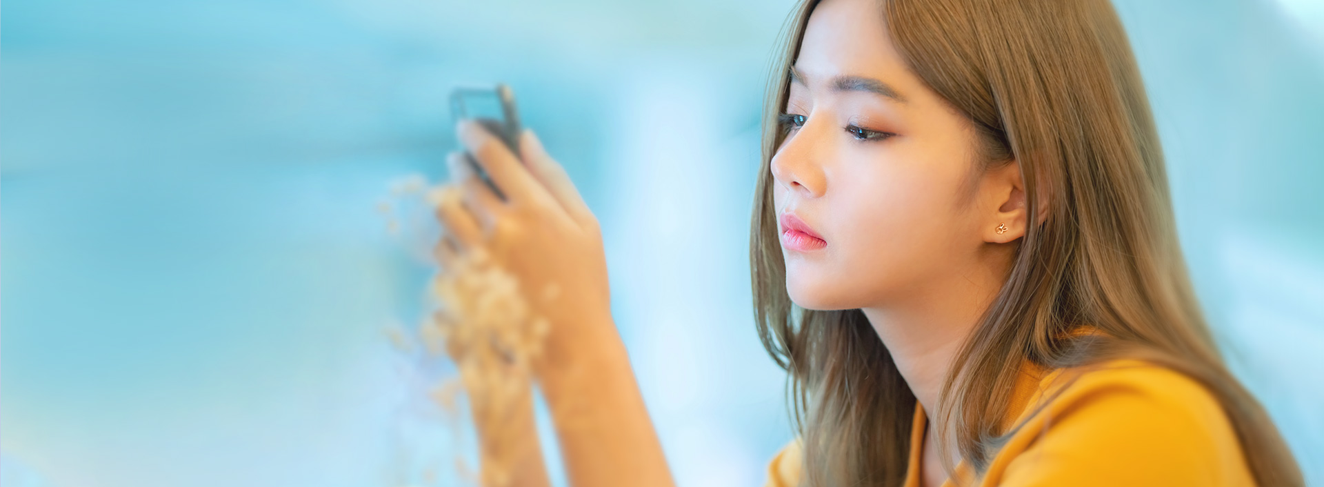Banner for Flat Nose Rhinoplasty showing a woman looking at her smartphone with a natural and distinct facial profile