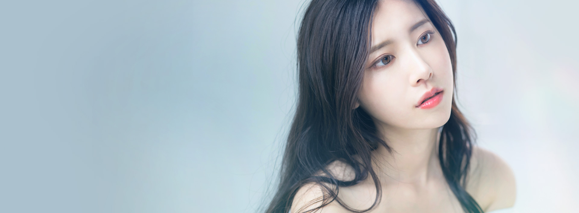 Profile photo of a long-haired woman with bare shoulders gazing gently forward for the Implant-Free Rhinoplasty page header