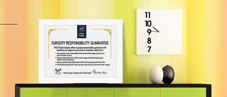 Framed surgical warranty certificate of APEX Plastic Surgery on a shelf next to a square wall clock