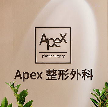 燈光映照下的診所室內牆面 APEX 整形外科英文與韓文招牌標誌