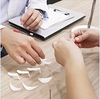 상담 테이블 위 다양한 코 및 턱 보형물 샘플을 두고 의료진이 손짓하며 맞춤 성형 상담을 진행하는 모습