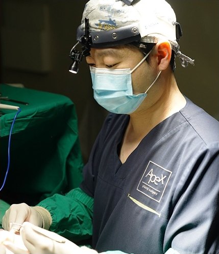 헤드라이트와 마스크를 착용한 에이펙스성형외과 의료진이 눈썹거상술을 집도하고 있는 모습