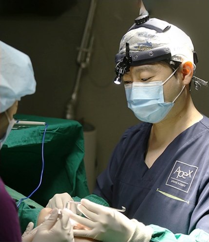 헤드라이트 루페와 마스크를 착용한 집도의가 수술실에서 세밀하게 눈재수술을 집도하는 모습