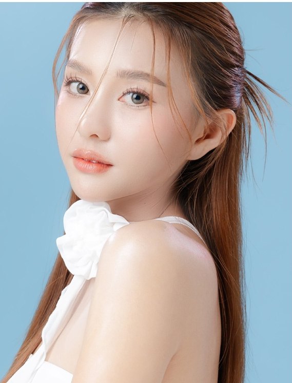 하늘색 배경에서 어깨 너머로 돌아보며 자연스러운 코와 이목구비를 드러낸 긴코 및 화살코 성형 모델의 프로필 모습