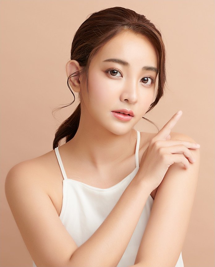 베이지색 배경 앞에서 흰색 민소매 탑을 입고 손가락을 얼굴 옆으로 들어 올린 여성의 복코 성형 모델 모습