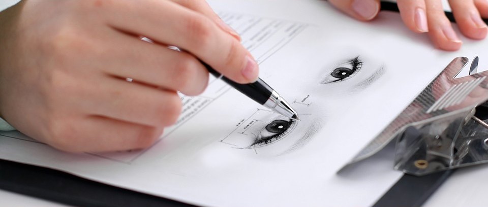 ภาพมือของแพทย์ใช้ปากกาหมึกซึมวาดดีไซน์ชั้นตาบนกระดาษที่มีภาพจำลองรูปตา โดยมีเครื่องมือผ่าตัดวางอยู่ทางด้านขวา