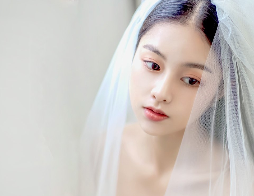 ภาพโคลสอัปใบหน้าและช่วงไหล่ของนางแบบเจ้าสาวสวมผ้าคลุมหน้าผ้าทูลล์สีขาว