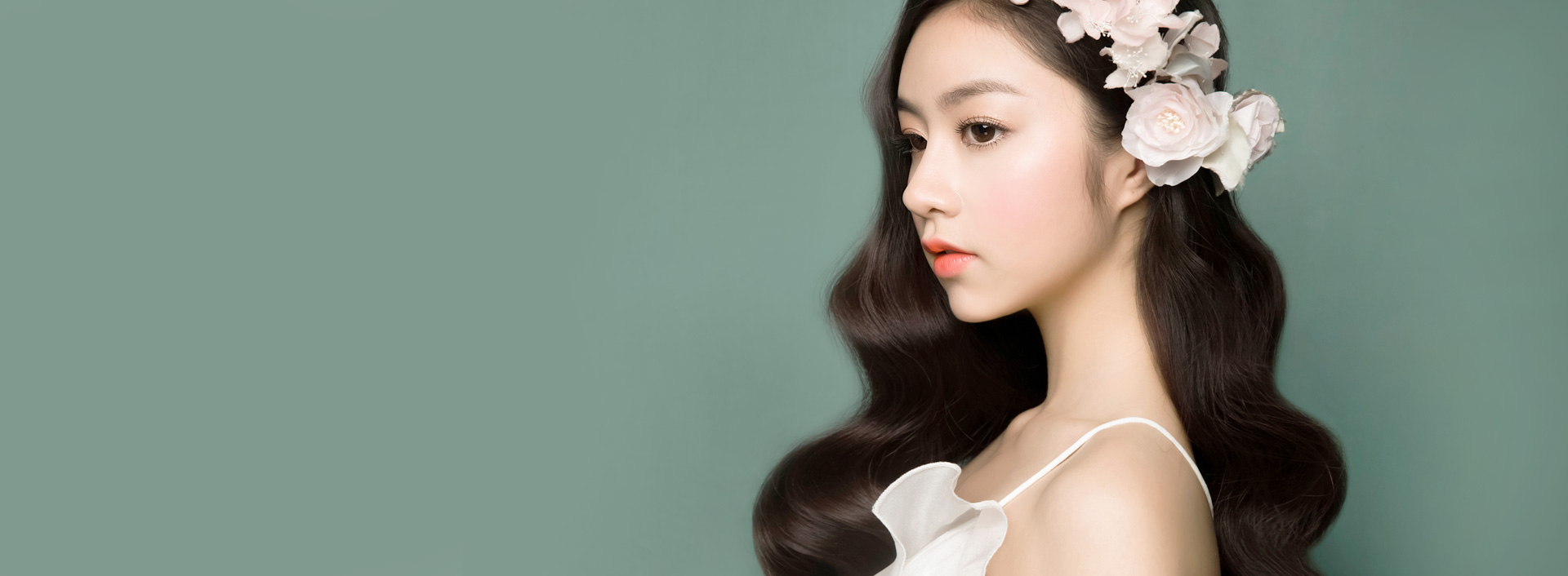 แบนเนอร์ศัลยกรรมจมูกฮัมพ์ รูปนางแบบผมดัดลอนประดับดอกไม้เผยให้เห็นสันจมูกที่เรียบเนียนและแนวด้านข้างบนพื้นหลังสีเขียวสบายตา