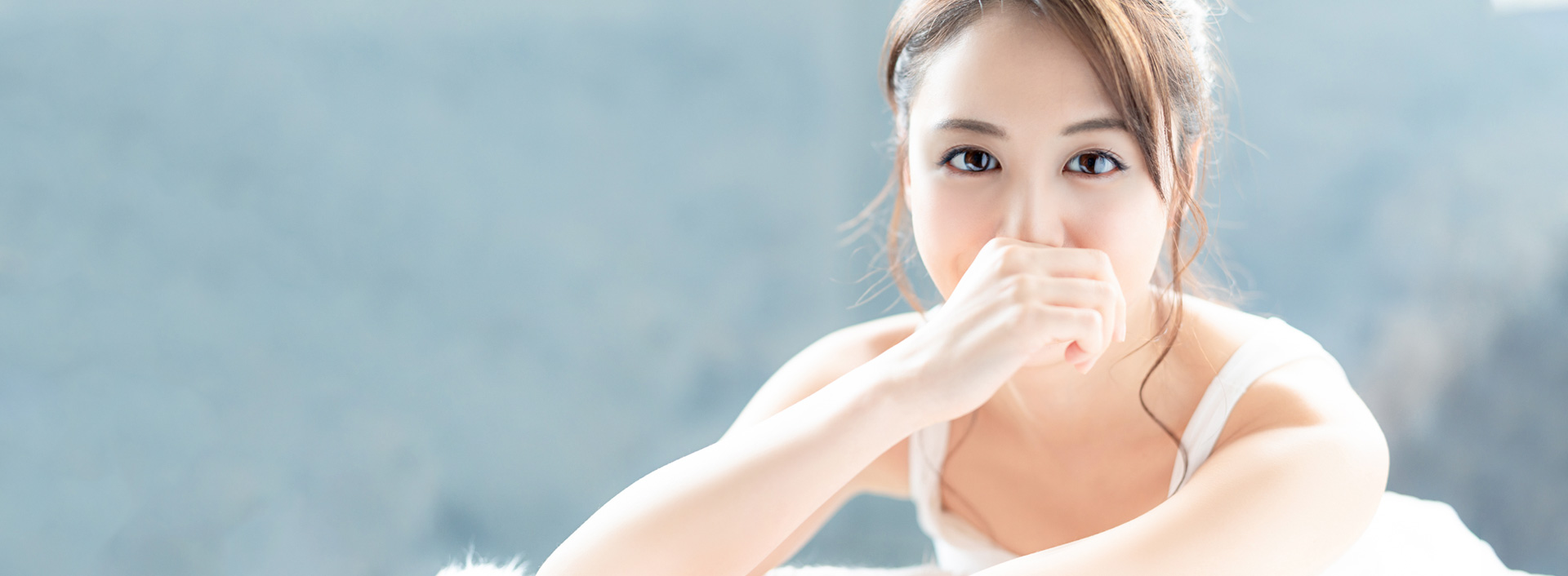 Người mẫu nữ với ánh mắt trong trẻo nhìn thẳng, tay che khóe miệng ở phần đầu trang dịch vụ tiêm Rejuran